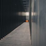 Explore a narrow, dimly lit corridor with modern architectural elements and soft light reflections.